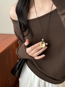Close-up detail of a matte gold irregular pendant necklace on a minimalist black cord