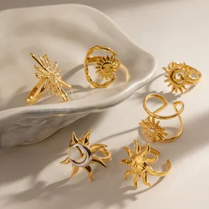 Vista detallada de anillos celestiales de acero dorado con motivos de sol y piedra