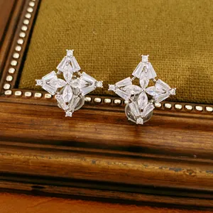 Dettaglio di orecchini a clip a fiore placcati oro 18k con scintillanti pietre di zirconi.