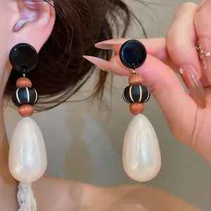 Close-up of retro teardrop pearl earrings with wooden beads and black accents