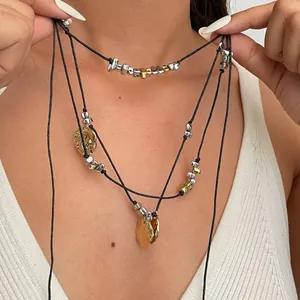 Dettaglio collana multistrato con cordoncino in pelle e ciondoli petali di metallo.