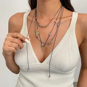 Primo piano di una collana chic a più strati in cuoio con ciondoli a petalo di metallo stropicciato