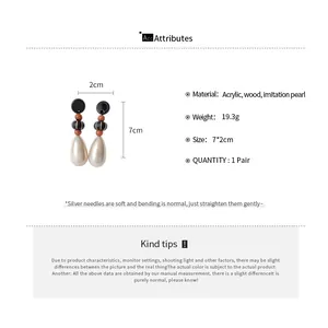 Detail view of retro teardrop pearl earrings with wooden beads and silver needles.