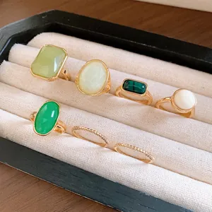 Close-up of 7 resin rings in square and oval shapes displayed in a velvet tray.