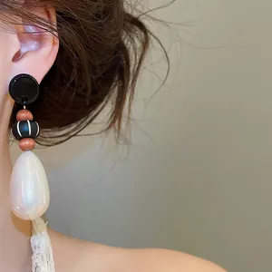 Detail view of retro water drop pearl earrings with wood beads and silver needle