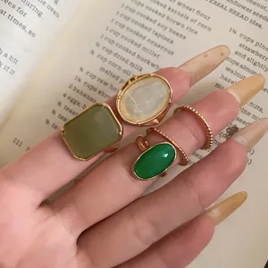 Detail view of a resin ring set featuring green and white stones on a vintage book.