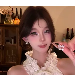 Detail view of Korean style silver bow earrings with sparkling zircon and pearl accents