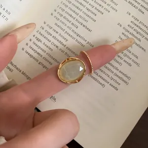 Close-up detail of vintage style gold resin oval ring and beaded band worn on finger
