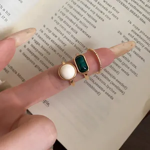 Close-up of vintage-style gold-tone rings with white and green resin stones.
