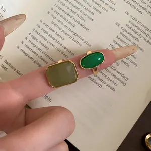 Detailed view of square and oval green resin rings with a gold-tone metal base.