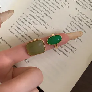 Close-up detail shot of vintage green resin rings with square and oval shapes on a finger.