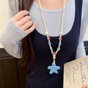 Primer plano de un collar de cuentas de colores con colgante de estrella de mar azul en una modelo.