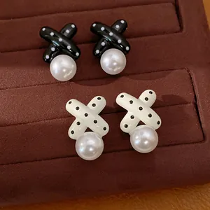 Detaillierte Nahaufnahme von eleganten X-förmigen Emaille-Ohrringen mit Polka Dots und Perlen
