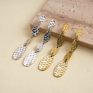Primo piano di orecchini pendenti geometrici ovali in metallo martellato vintage in argento e oro