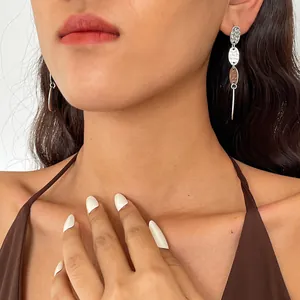 Primo piano di orecchini ovali plissettati in metallo antico indossati da una modella.