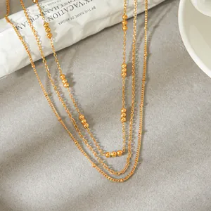 Close-up detail of a minimalist gold triple-layer necklace with elegant small round beads.