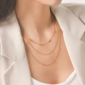 Detail view of elegant triple-layered gold beaded necklace worn on a woman's neck
