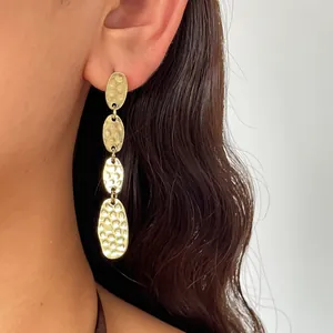 Dettaglio di orecchini a goccia ovali geometrici in oro martellato vintage su un modello