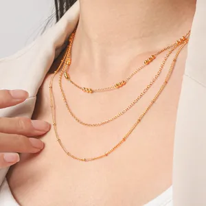 Elegant triple-layered gold bead necklace worn with a blazer for a chic and stylish look
