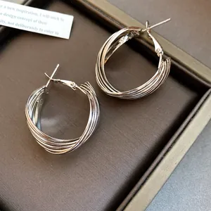 Nahaufnahme von eleganten mehrschichtigen C-förmigen Creolen in Silberoptik auf Display.