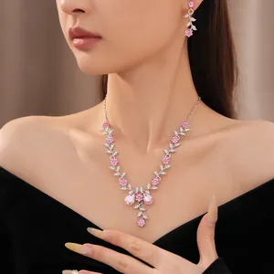 Nahaufnahme eines eleganten Schmucksets mit rosa Kristallblumen und Blättern auf Modell.