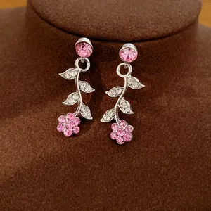 Nahaufnahme von eleganten Tropfenohrringen mit rosa Kristallblumen und Blattdesign