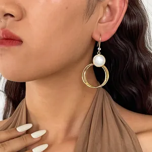 Primo piano di orecchini vintage in resina con cerchi geometrici dorati su modella