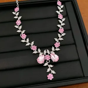 Detail einer Halskette mit rosa Strassblumen und Blättern in einer schwarzen Schmuckschale