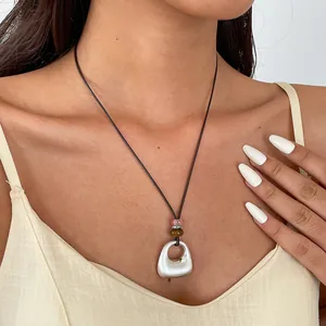 Détail d'un collier avec pendentif de style ethnique et perles sur un cordon marron