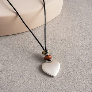 Gros plan d'un pendentif en céramique en forme de cœur sur un cordon noir ethnique
