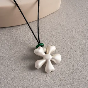 Détail d'un élégant collier à pendentif fleur en céramique blanche avec perle