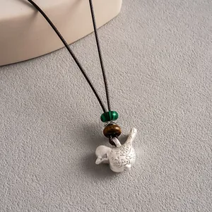 Gros plan d'un collier pendentif en forme d'oiseau ethnique avec perles en pierre et cordon.
