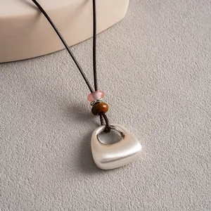 Gros plan d'un collier ethnique en cuir avec pendentif argenté et perles colorées