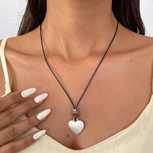 Vue détaillée d'un collier en cuir ethnique avec pendentif coeur argenté sur modèle