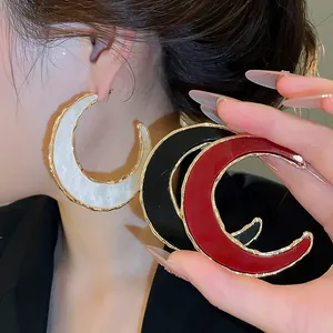 Nahaufnahme von übergroßen sichelförmigen Creolen in Weiß, Schwarz und Rot Design