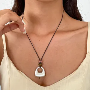 Détail d'un pendentif géométrique argenté sur cordon en cuir marron, style ethnique