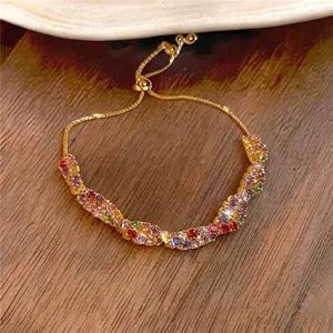 Bracciale dorato regolabile con pietre di zircone colorate su fondo in legno