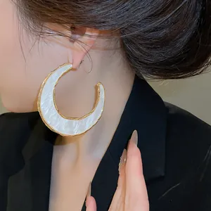 Detailansicht der großen C-förmigen Creolen mit weißem Acetat und goldenem Metallrand.