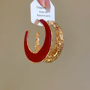 Detailaufnahme der goldfarbenen und roten C-förmigen Creolen auf der Displaykarte