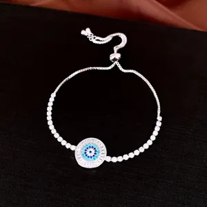 Détail d'un bracelet œil porte-bonheur réglable avec des zircons bleus et blancs.