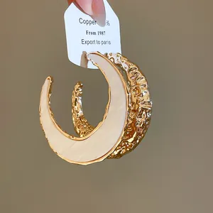 Detailansicht der goldenen C-förmigen Creolen mit glattem weißem Acrylinlay-Dekor