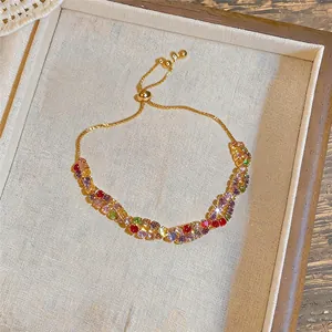 Détail de pierres de zircon colorées sur un bracelet doré ajustable torsadé