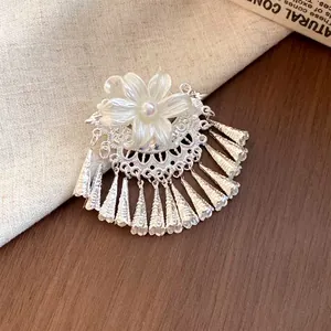 Detailopname van een zilveren haarspeld met parelbloem en hangende metalen kwastjes