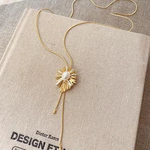 Vintage 18k gold-plated necklace with pearl sunburst pendant on textured linen book