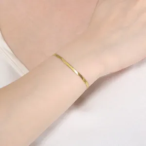 Detailaufnahme eines minimalistischen 18K vergoldeten Schlangenarmbands am Handgelenk