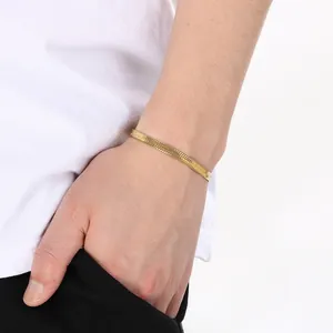 Detail eines minimalistischen 18K vergoldeten Edelstahl-Fischgräten-Armbands am Gelenk