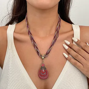 Detailweergave van een vintage druppelketting met hanger van hars en rode glanzende strass