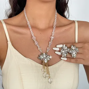 Gedetailleerde opname van elegante glazen bladkwastketting en strass oorbellen op het model