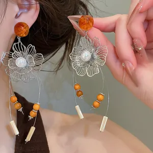Close-up detail of vintage hollow flower earrings with pearls and long tassels.