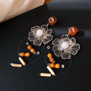 Macro view of silver flower earrings with resin beads and dangling pearl accents